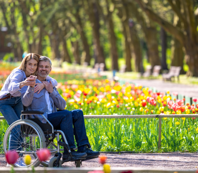 Man in a wheelchair and woman supporting