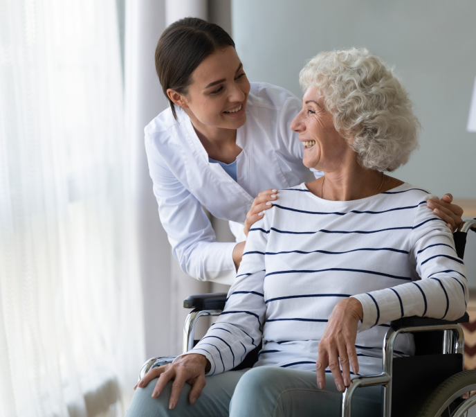 Woman in wheelchair smiling and getting support from a caregiver