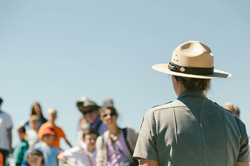 Female park ranger teaching tourists outdoors.