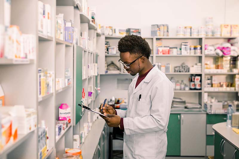 Man pharmacist making notes on clipboard.