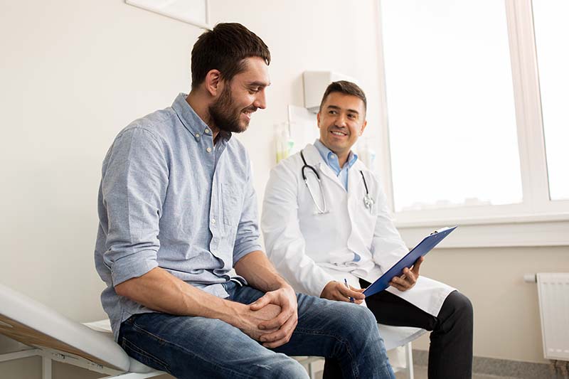 Male PCP chats with patient.